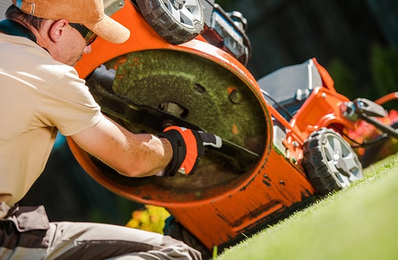 Landscaper clearing the blade on a lawn mower