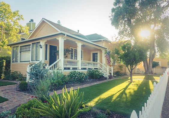 Yellow  bungalow with a white picket fence and a well maintained yard